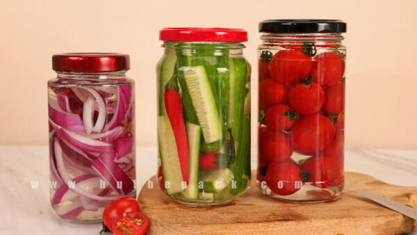 Tall glass jars holding pickled vegetables with metal lids