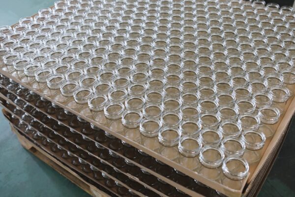 Rows of empty glass jars stacked on protective sheets